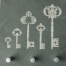 Das Schieferrelief "Schlüsselbrett" zeigt fünf weiße Vintage-Schlüssel auf Grau über drei metallischen Haken - dekorativ und praktisch zugleich. Wertica Shop