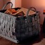 Der graue Filzkorb mit Kaminholz steht neben einer Kerze auf einem Hocker und schafft eine warme, gemütliche Atmosphäre im Raum. Wertica Shop