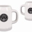Zwei weiße Keramiktassen mit Henkeln zeigen das schwarze "Geschenkpapier 'Zimmerer'"-Logo mit Bergen, Wasser und Händen auf weißem Hintergrund. Wertica Shop