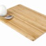 Ein hartgekochtes Ei und ein silberner Löffel sitzen auf dem Magischen Holz-Vesperbrett, ein rechteckiges Bambusbrett vor weißem Hintergrund. Wertica Shop