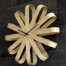 Die Design-Wanduhr "Buche" aus gebogenen Holzstreifen und schwarzen Zeigern setzt als modernes Wohnaccessoire Akzente auf dunkler Fliesenwand. Wertica Shop